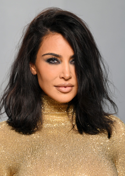 Kim Kardashian wears a glittery gold turtleneck dress and colored contacts.